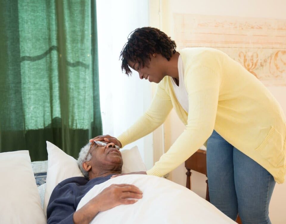 caregiver standing next to senior man in bed