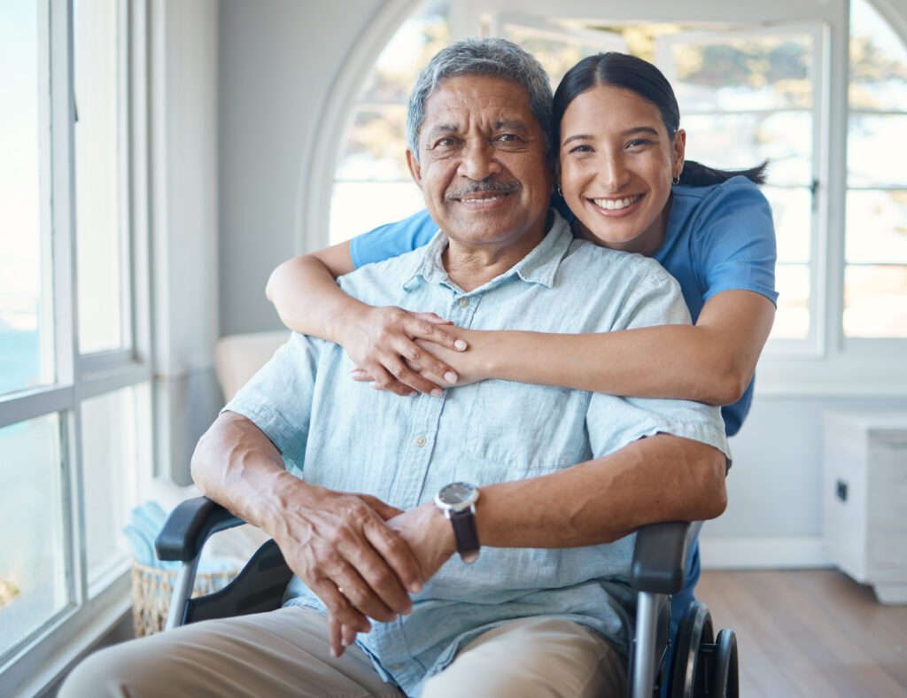 Caregiver hugging senior man in wheelchair