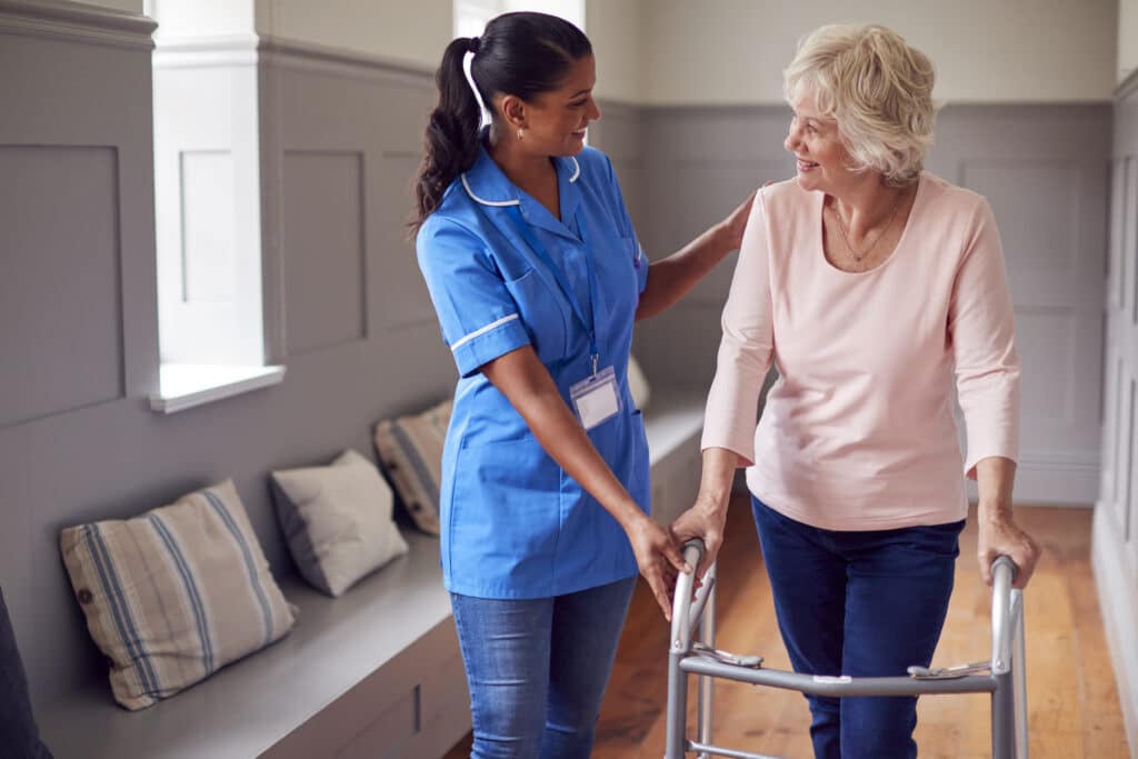 senior woman at home using walker and being helped