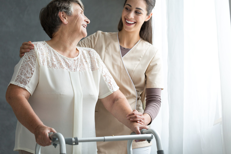 caregiver helping senior woman using walker