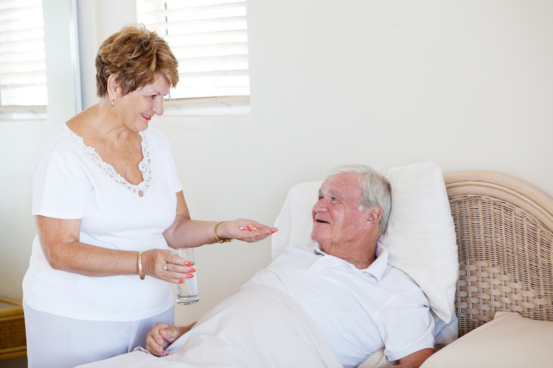 caregiver helping senior man wake up and take medicine